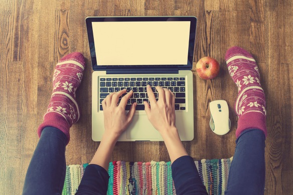 Woman's hands typing on laptop keyboard. Study and work online, freelance, worm socks, winter, home comfort and relax